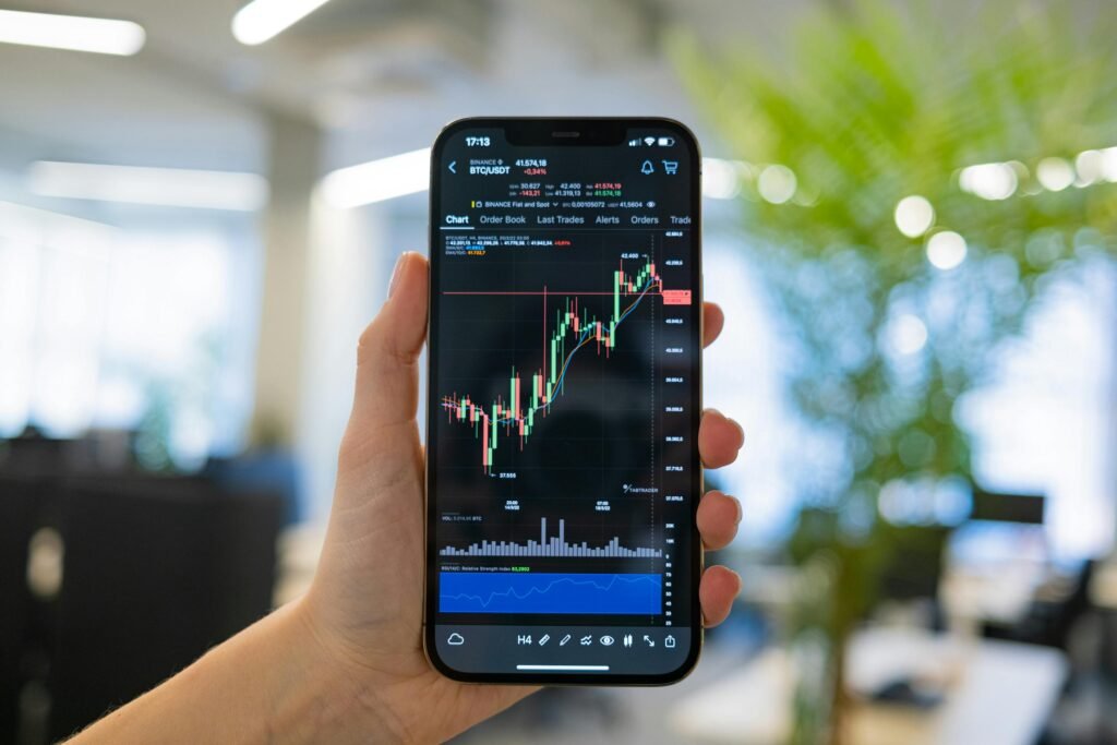A person holding a smartphone displaying a cryptocurrency chart in an office setting.